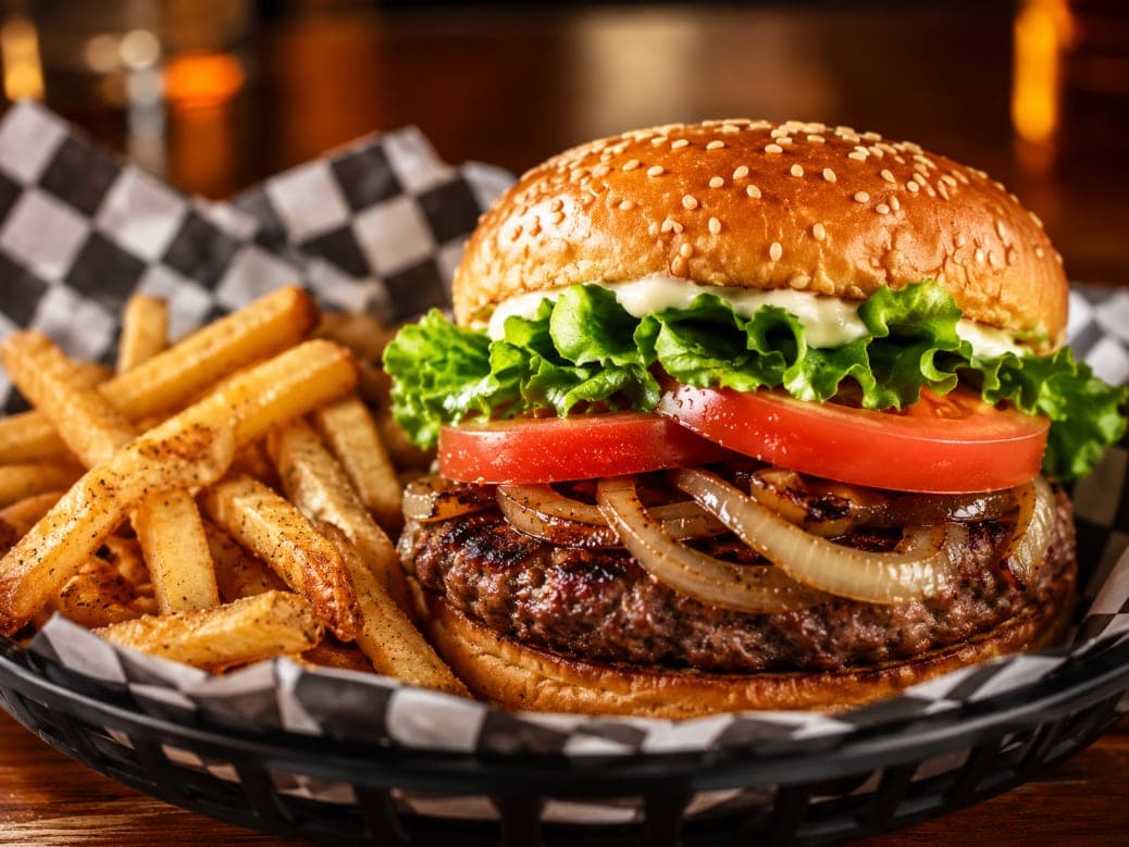 The Classic Burger with grilled onions, lettuce and tomato, served with fries.