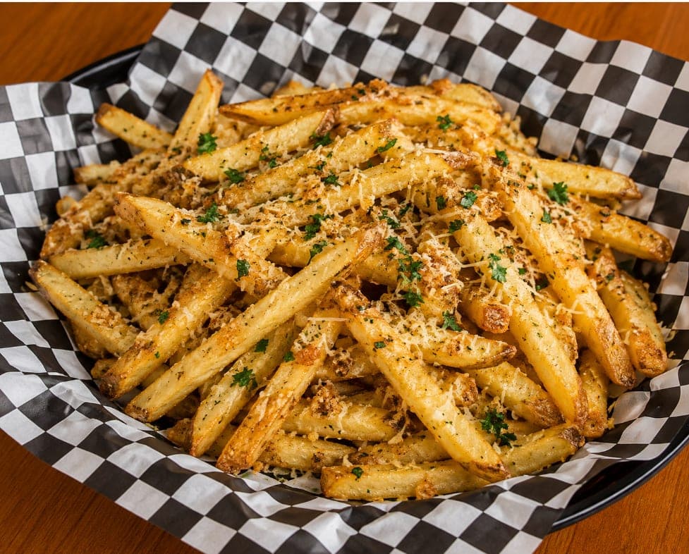 A basket of garlic fries under shredded parmesan and parsley.