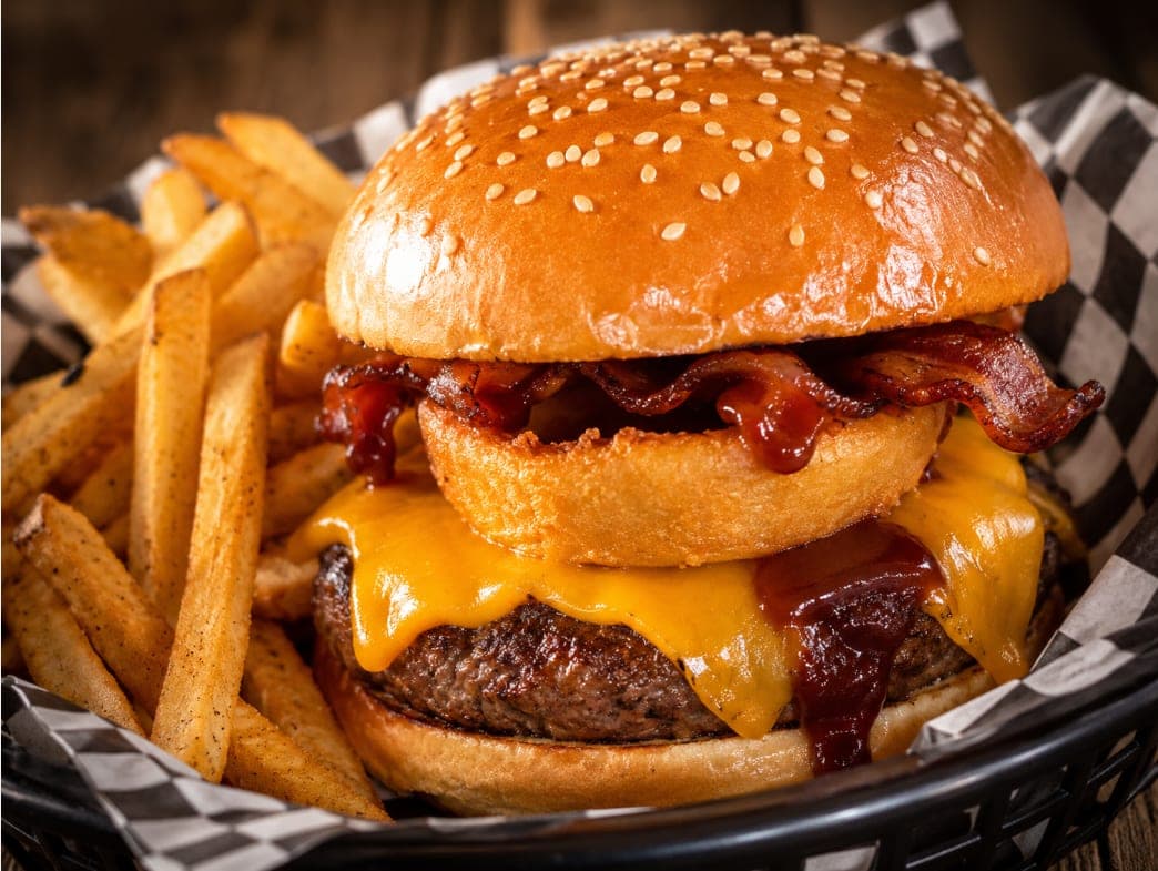 The Go West Burger with cheddar cheese, an onion ring, bacon and BBQ sauce, served with fries.