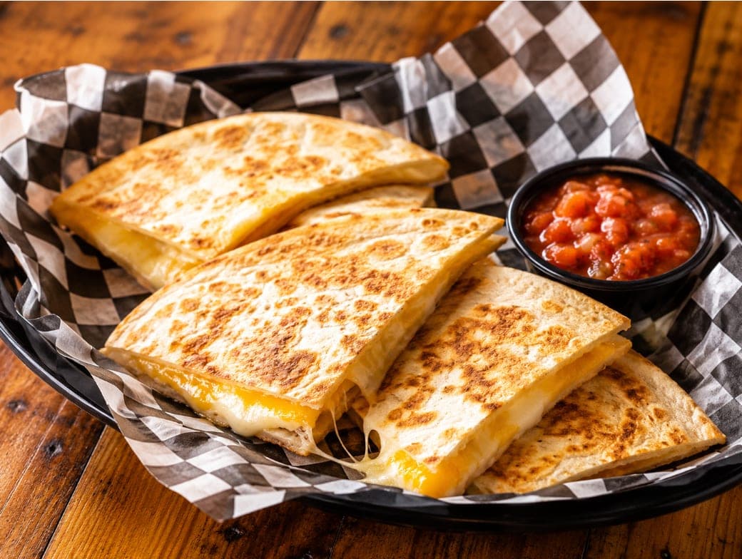 A cheese quesadilla cut into wedges with a side of salsa.