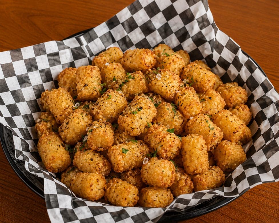 A basket of seasoned tater tots finished with parmesan and parsley.