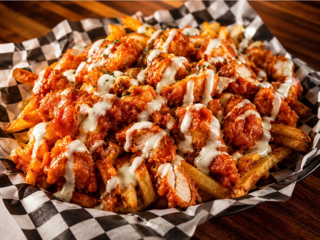 Fries piled with sauced chicken and drizzled with ranch.
