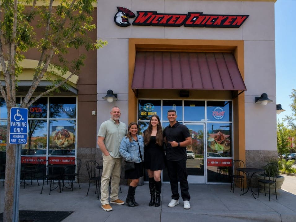 Four people standing together under the Wicked Chicken sign at the Santa Clarita storefront.